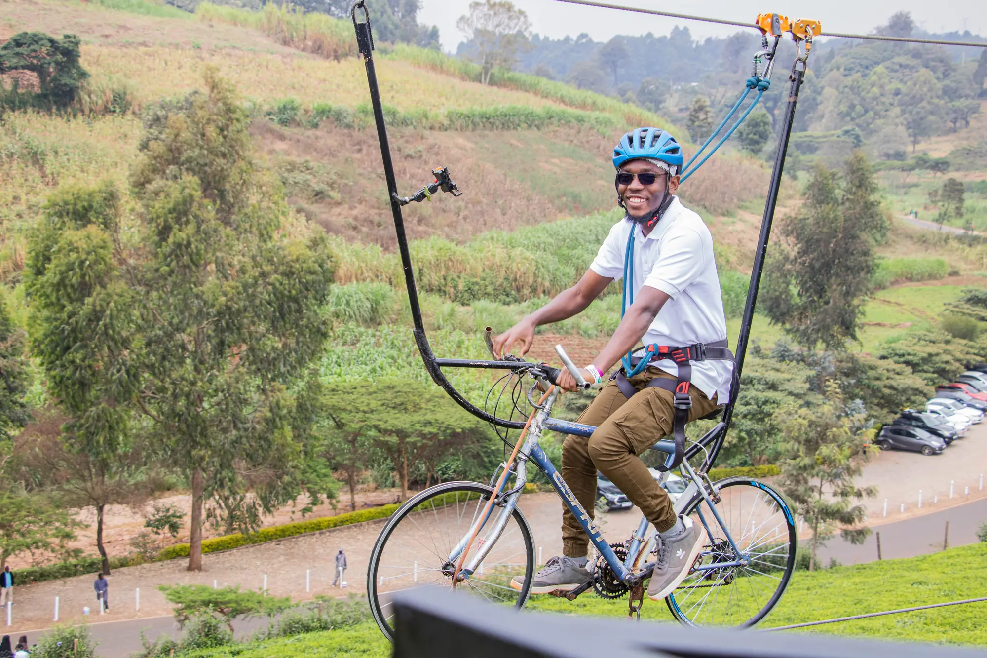 A rider in a blue helmet sky cycling on a cable high above the Tigoni tea fields