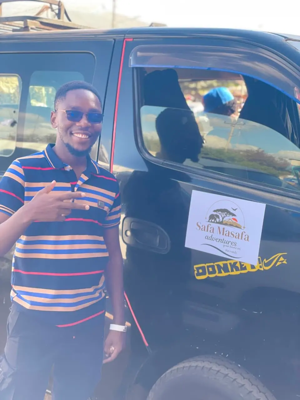 A Safa Masafa driver giving a thumbs up beside a branded tour vehicle